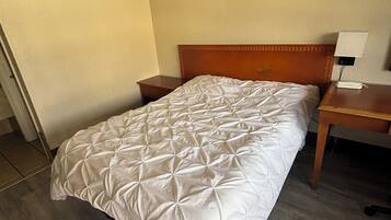 A single bed with a wooden headboard, a bedside table, and a nightstand with a lamp.