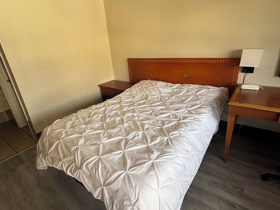 A single bed with a wooden headboard, a bedside table, and a nightstand with a lamp.