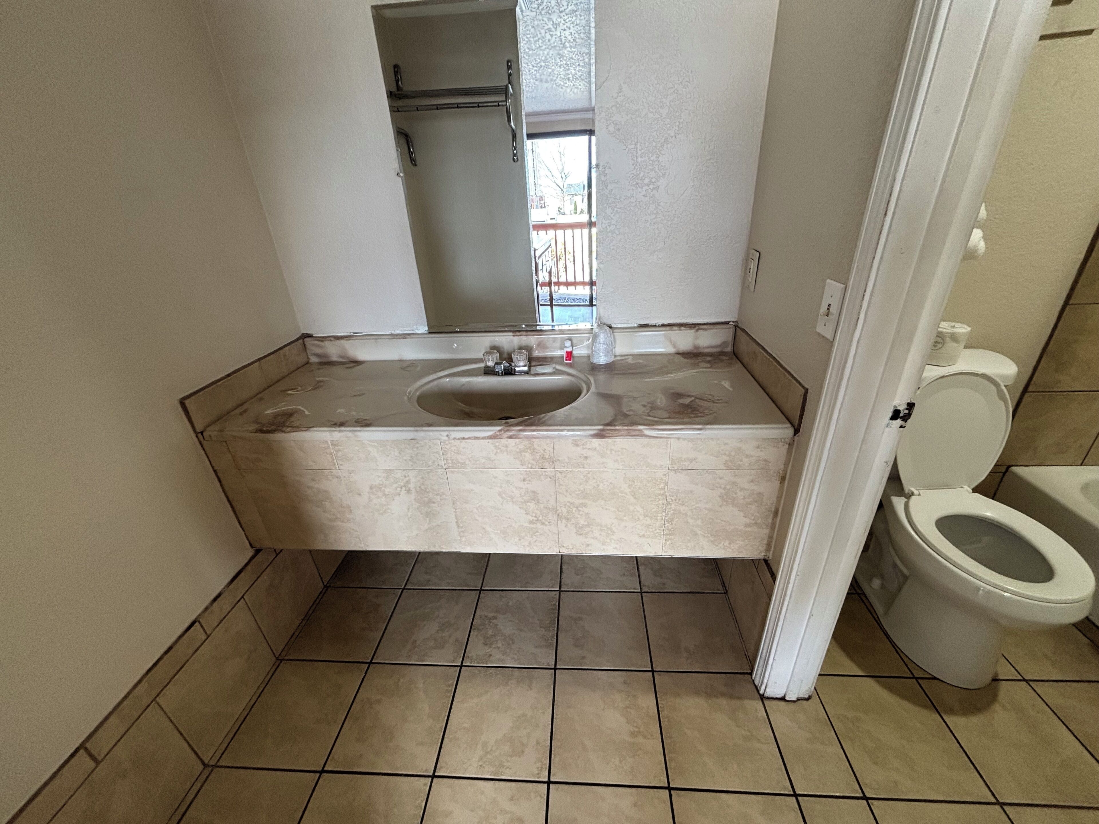 A bathroom with a sink, toilet, and a mirror.