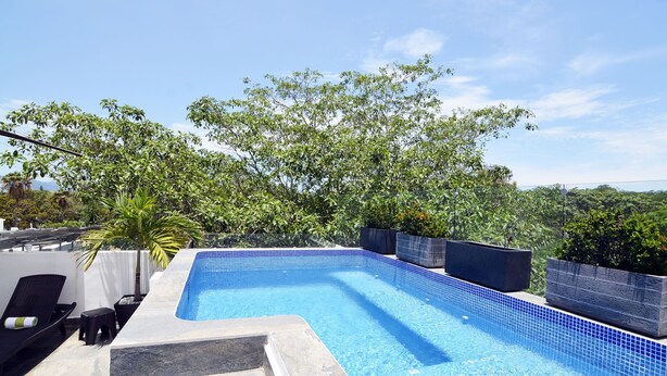 A rectangular swimming pool with blue tiles, surrounded by a stone deck and black planters. - CasMar - 4 (Puerto Vallarta)