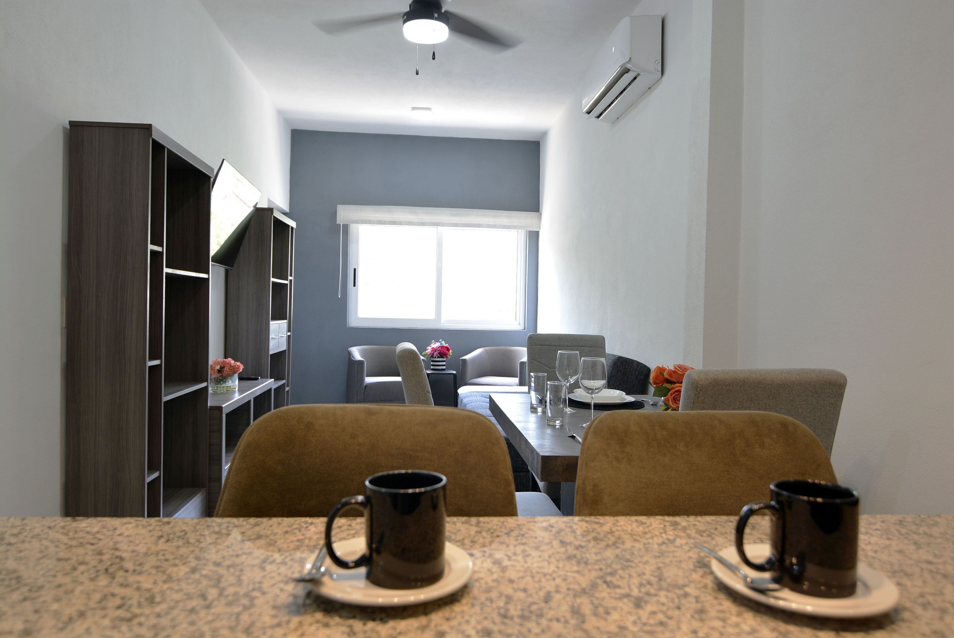 A modern dining area with a granite table, two chairs, and a ceiling fan.