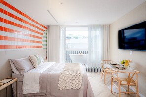 Relax in a stylish room with a large bed, flat-screen TV, and a small balcony with a seating area.