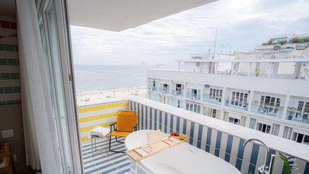 A balcony with a bathtub, a chair, and a towel rack. - Sea View and Balcony With Bathtub PI Premium (Rio de Janeiro)