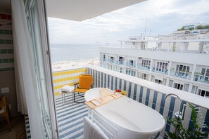 En balkon med et badekar, en stol og et håndklædetørrestativ.