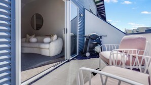 Un patio moderno con una silla blanca, un sofá y un patinete.
