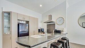 Una cocina moderna con una isla central, taburetes de bar, horno empotrado y microondas.