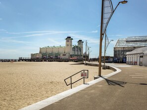 Een promenade aan zee met een houten looppad, een pier en een groot gebouw met meerdere verdiepingen en een toren.