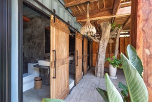 A wooden interior with a tree, a hanging light fixture, and a white sink.