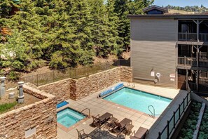 Un área de piscina con dos piscinas, paredes de piedra y mobiliario exterior.