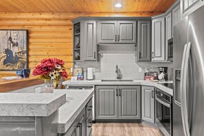 Una cocina moderna con armarios grises, un refrigerador de acero inoxidable y un techo de madera.