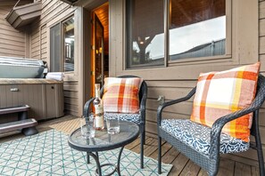 A wooden deck with two wicker chairs, a small round table, and a hot tub. - Walk to Ski Slopes + Trails! Cozy 2-Bedroom, Recently Renovated Condo with Pool, Hot Tub, BBQ, and A/C | BBL-351A by KBM Resorts (Park City)