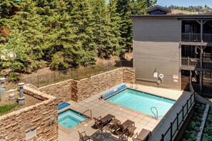 A pool area with two pools, stone walls, and outdoor furniture.