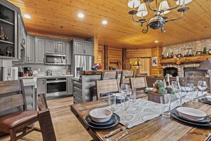 Interior acogedor de una cabaña con comedor listo para una comida, cocina con electrodomésticos modernos y chimenea de piedra.