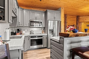 A modern kitchen with grey cabinets, stainless steel appliances, and a wooden ceiling. - Walk to Ski Slopes + Trails! Cozy 2-Bedroom, Recently Renovated Condo with Pool, Hot Tub, BBQ, and A/C | BBL-351A by KBM Resorts (Park City)