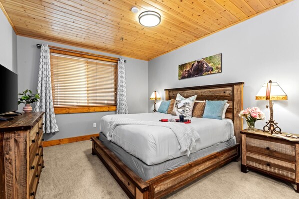 Un dormitorio con una cama de madera, televisor, escritorio y lámpara.