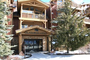 A lodge with a wooden facade, a balcony, and a sign reading 'BLACK BEAR LODGE'.