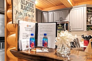 Un interior de madera con un cartel de Alpine Racing, un folleto de bienvenida y una botella de agua Fiji sobre una mesa.