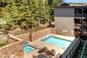 Un área de piscina con dos jacuzzis, paredes de piedra y una terraza de madera.