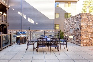 An outdoor patio with a grill, table, and chairs.