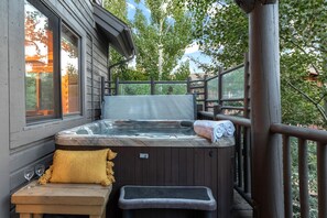 Un bain à remous sur une terrasse en bois, avec un banc et une serviette.