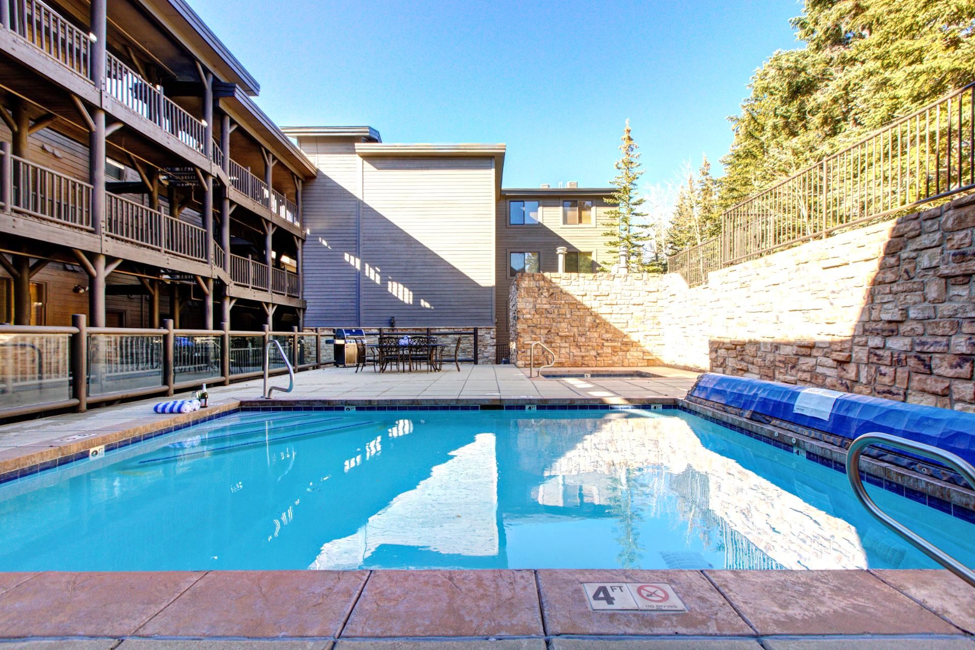 A pool area with a stone wall and a wooden deck.