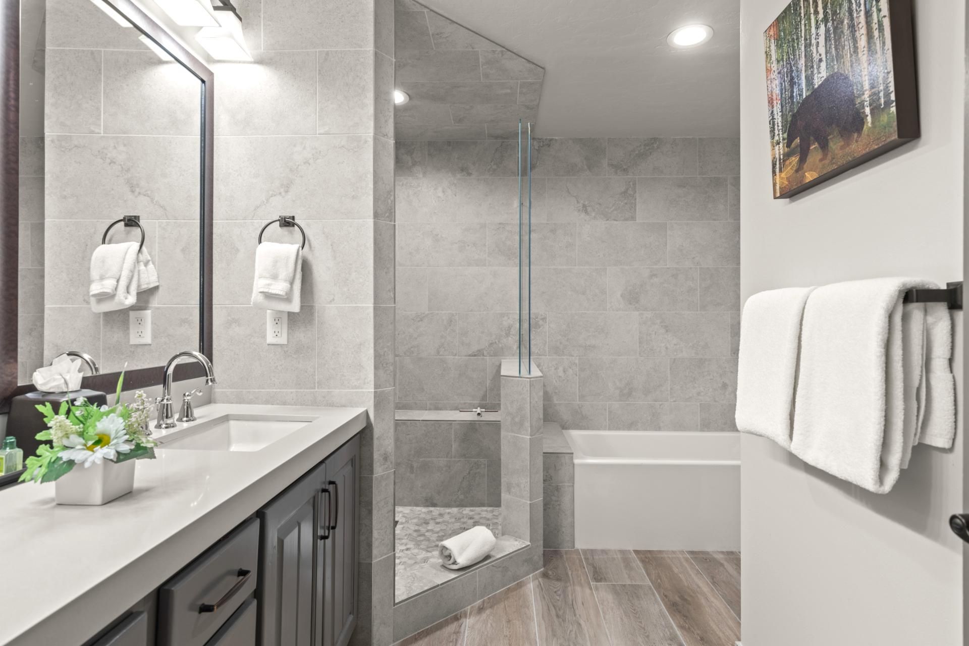 Een moderne badkamer met een douche, een badkuip en een grote spiegel.