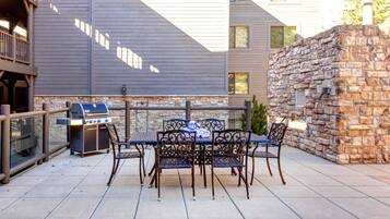 An outdoor patio with a grill, table, and chairs.