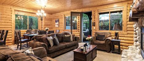 L’intérieur d’une cabane en rondins comprend un coin repas, des canapés et une cheminée.