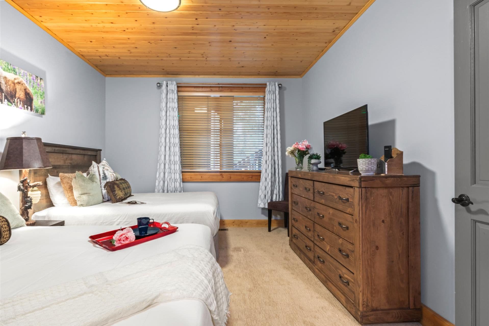 Un dormitorio con dos camas, un aparador de madera, un espejo y una ventana con persianas.