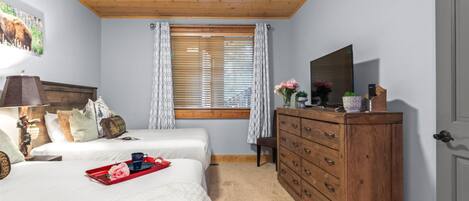 Un dormitorio con dos camas, un aparador de madera, un espejo y una ventana con persianas.