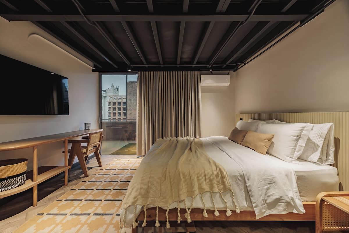 Ein modernes Hotelzimmer mit einem großen Bett, einem Schreibtisch und Blick auf die Stadt.
