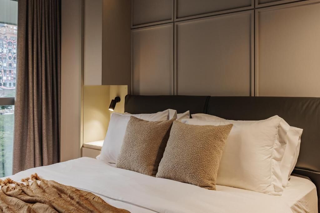 A hotel room with a large bed, a headboard, and a window with curtains.