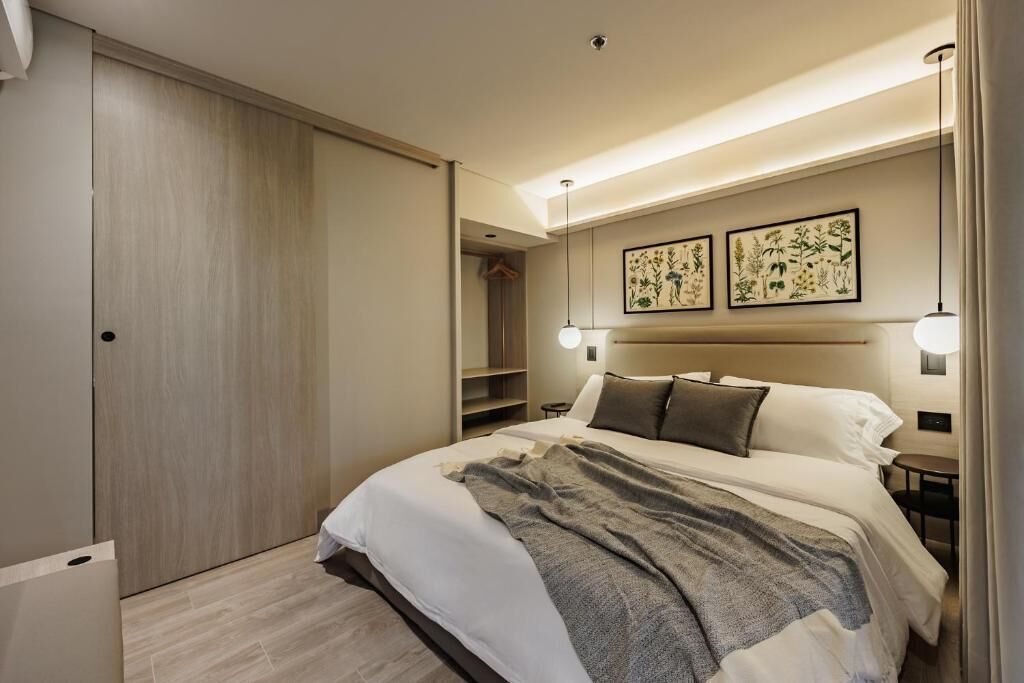 A modern hotel room with a large bed, a wardrobe, and two wall-mounted lights.