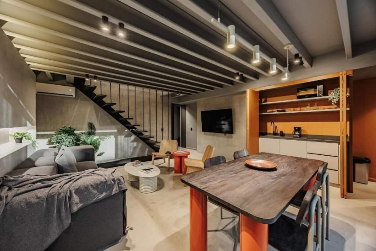 Ein modernes Wohnzimmer mit Essbereich, Treppe und Küche.