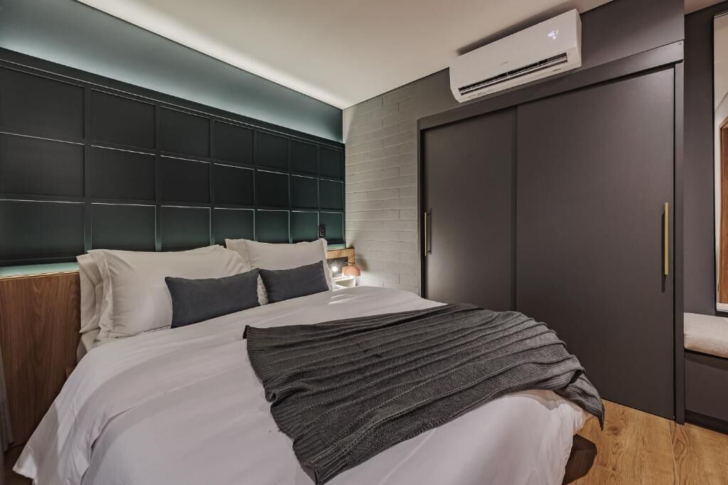 A modern bedroom with a large bed, a dark headboard, and a wardrobe.