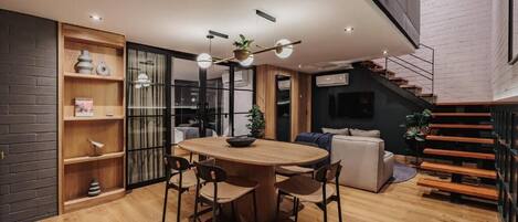 Un interior moderno con una mesa de comedor de madera, sillas, un sofá y una escalera.
