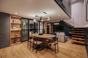 A modern interior with a wooden dining table, chairs, a sofa, and a staircase. - H10 Provenza (Medellín)