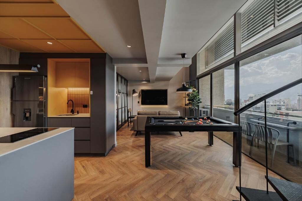 Cozinha moderna com área de refeições, um sofá e uma grande janela com vista para a cidade.