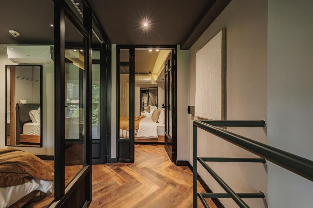 Una habitación de hotel moderna con piso de madera, una cama grande, un escritorio y un ventanal.