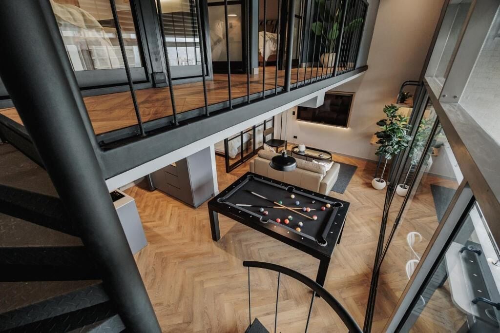 Un moderno espacio tipo loft con mesa de billar, sofá y mesa de comedor.