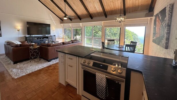 A modern kitchen with a large island, built-in oven, and a dining area with a view.