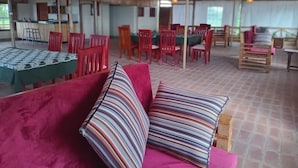 A spacious dining area with red chairs and tables, a wooden ceiling, and hanging light fixtures. - ngirisi hill silverback  lodge-bwindi (Bwindi)