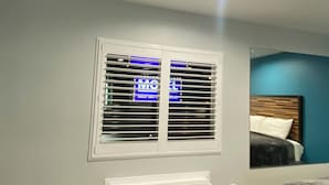 A bedroom with a bed, a window with blinds, a wall-mounted air conditioner, and a ceiling light. - Plaza inn Motel - Los Angeles area (Rosemead)