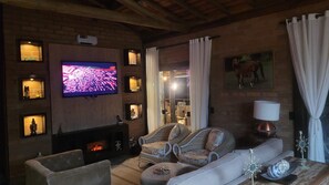 Un salon chaleureux avec une cheminée, un téléviseur, des meubles en osier et une lampe.