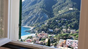 A coastal town with buildings on a hillside, a beach, and a rocky cliff. - Historical Villa 'The Birdhouse' - Garden & Views (Monterosso al Mare)