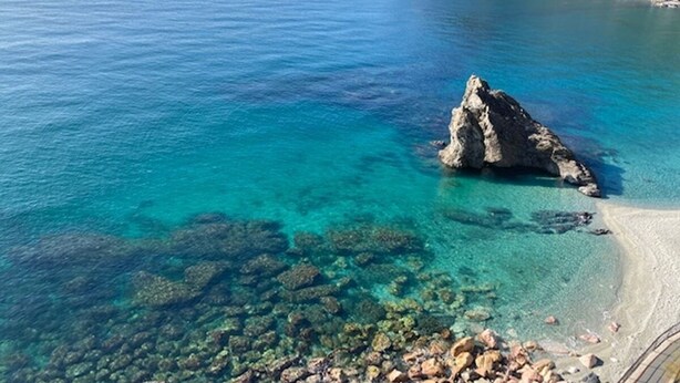 A coastal landscape with clear turquoise waters, a rocky outcrop, and a sandy beach. - Paola Cosy Apartment with A/C near best beaches (Monterosso al Mare)