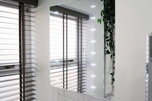 Ein modernes Zimmer mit großem Fenster, Jalousien und einer Wand-Klimaanlage.