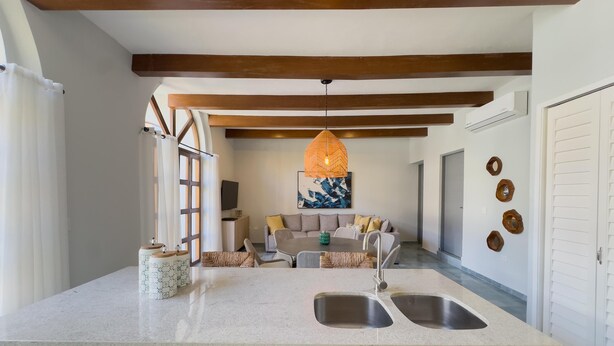 A modern kitchen with a large island, double sinks, and a dining area with a sofa and cushions. - Centro Historico on the Malecon Boardwalk (Mazatlan)