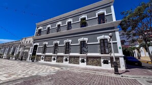 A historic building with a flat roof, multiple windows with metal bars, and a paved street in front. - Centro Historico on the Malecon Boardwalk (Mazatlan)