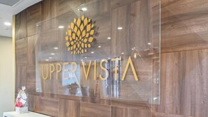 A reception area with a wooden wall and a glass panel displaying the words "UPPER VISTA" and a logo. - Niagara Falls Penthouse | Great Views | Gym | Luxe (Niagara Falls)